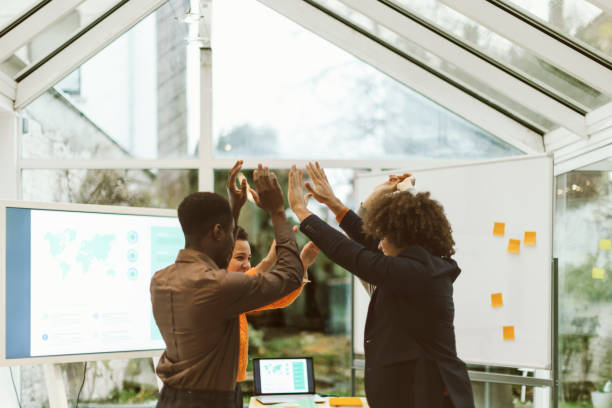 Members of a project management team high-fiving following their successes in implementing project management best practices for their client.